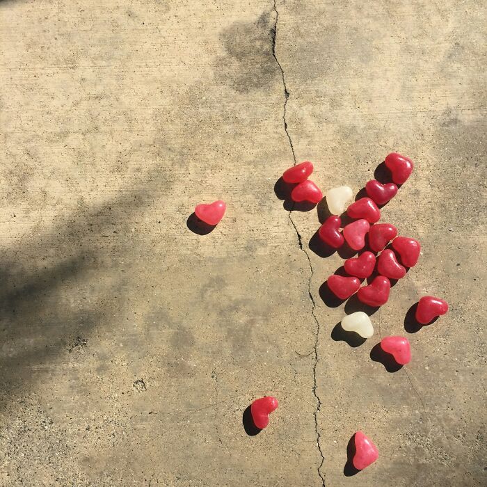 Red and white heart-shaped candies scattered on cracked concrete.