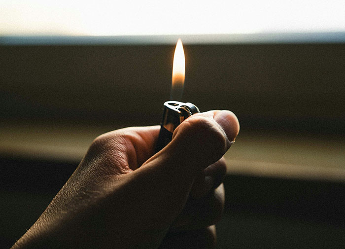 Hand holding a lit lighter, demonstrating using things wrong way.