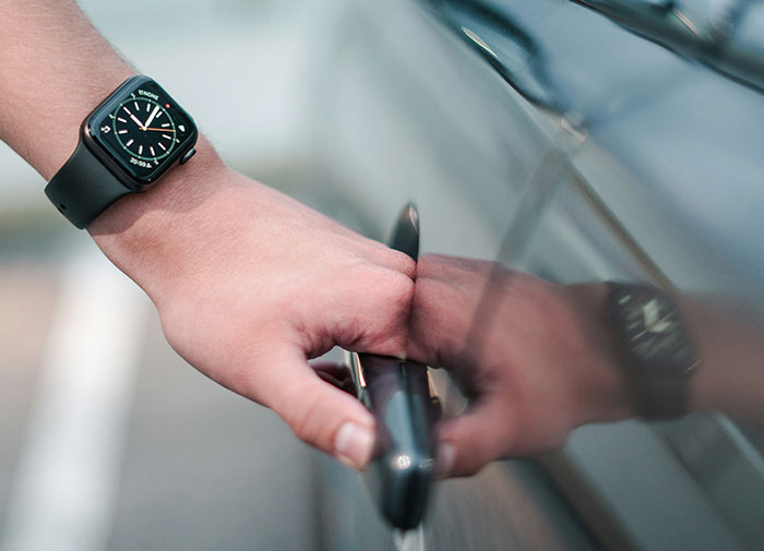 Hand wearing a smartwatch mistakenly trying to open a car door, highlighting using-things-wrong-way.