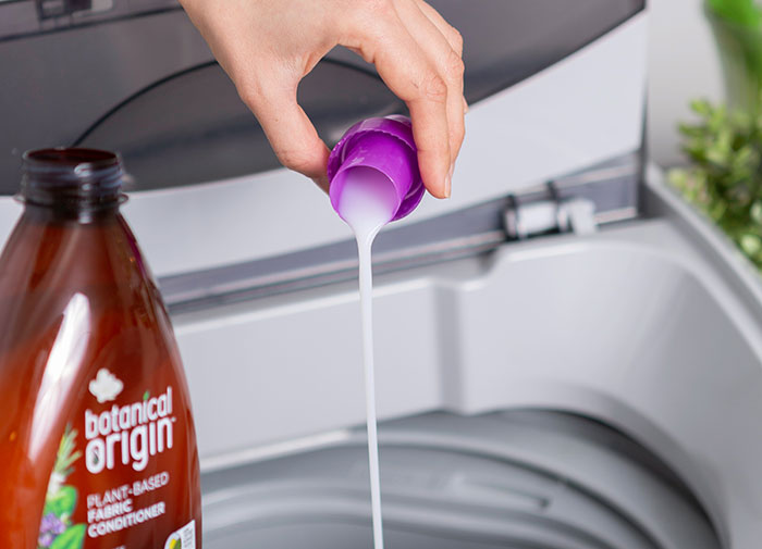 Pouring fabric conditioner using a cap into a washing machine, illustrating using things the wrong way.