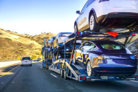 A car transporter carries new Tesla Model 3 vehicles along the highway, California, US. Credit: Andrei Stanescu / Alamy Stock Photo. R6HR26