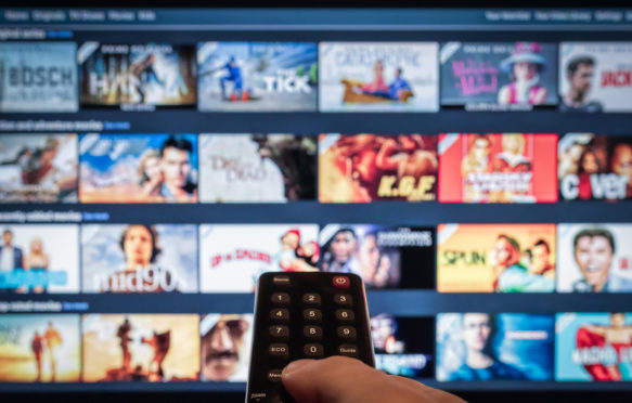 A remote control pointed to a smart tv showing a selection of on-demand video streaming services