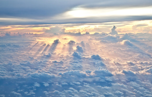 Sun rays shine through the clouds as dusk approaches.