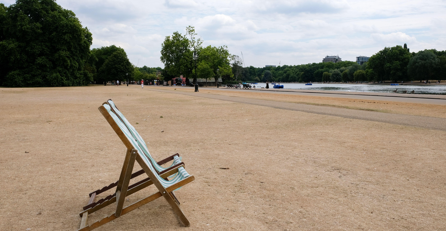 Scorched grass and empty deck chairs in Hyde Park, London, UK, during the heatwave in July 2022. Credit: Matthew Chattle / Alamy Stock Photo.