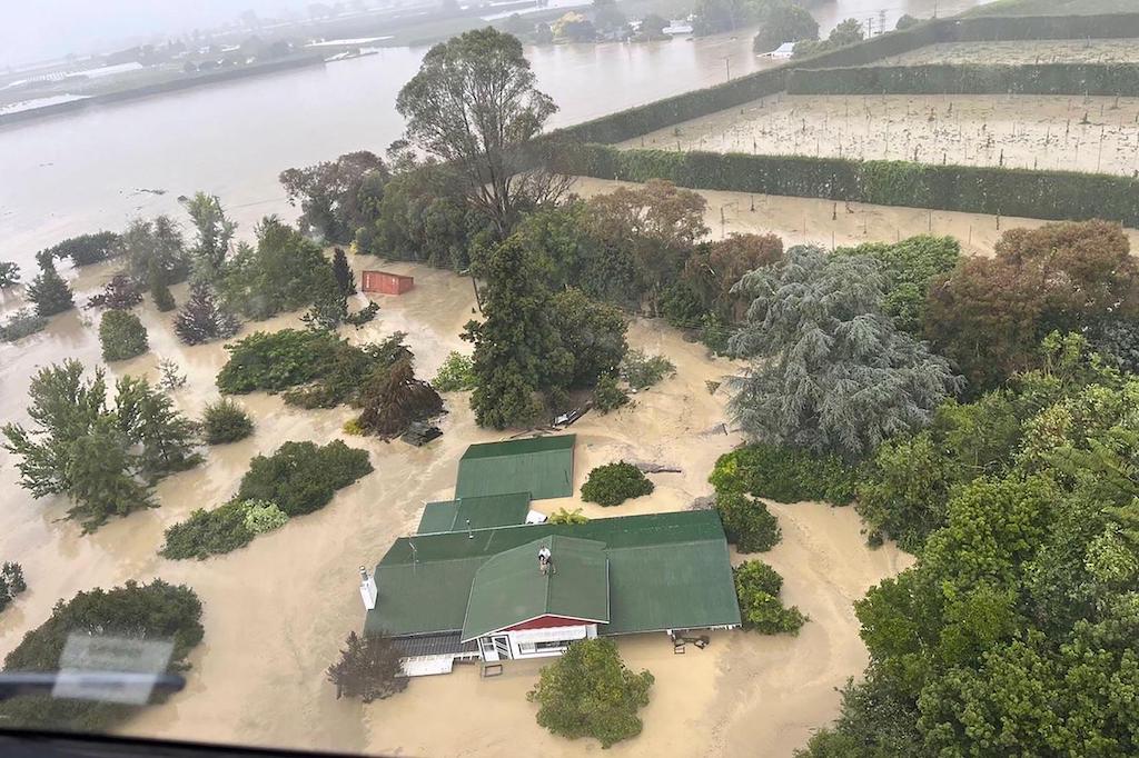 People standing on a rooftop waiting to be winched to safety by helicopter during floods caused by Cyclone Gabrielle, Esk Valley, New Zealand, February 15 2023.