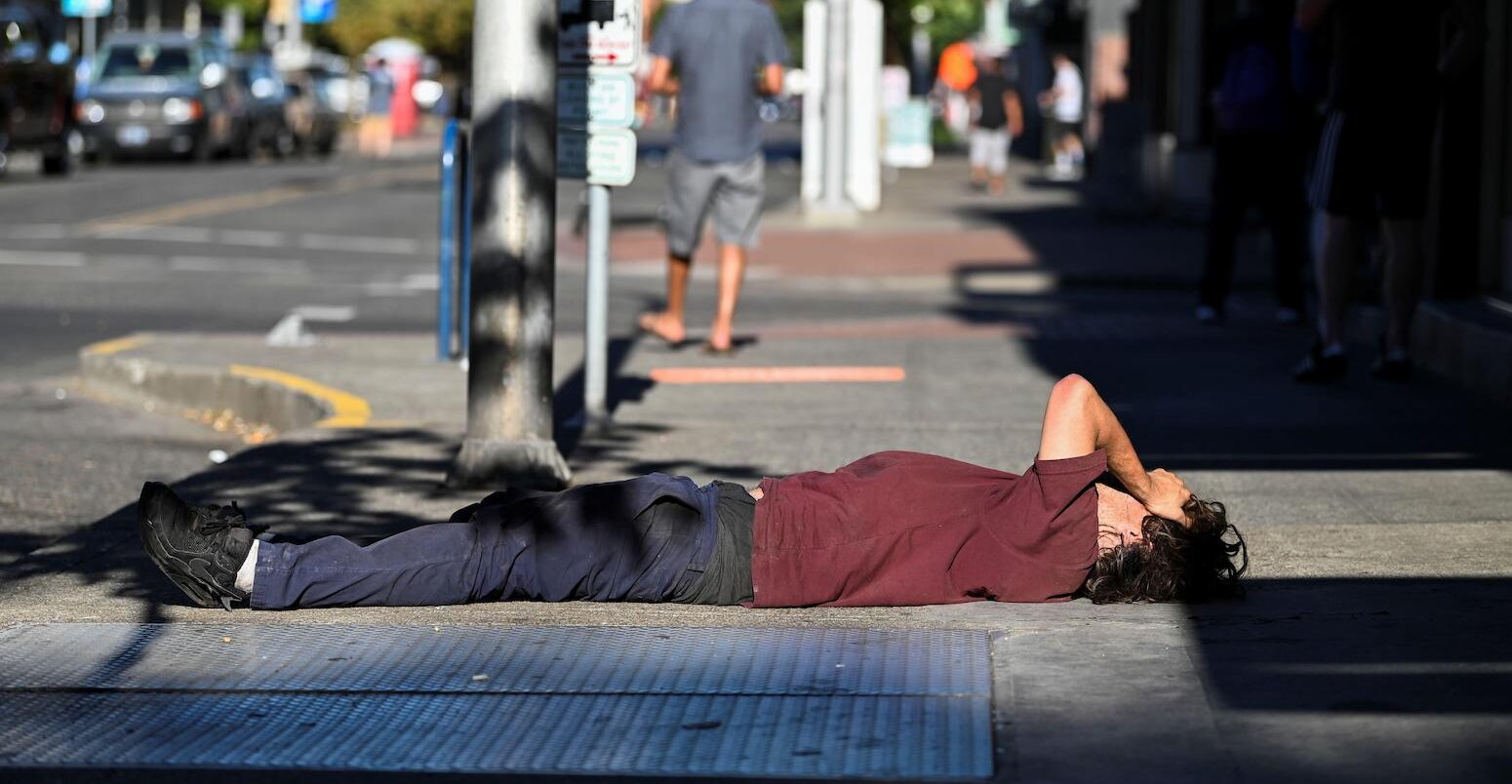 A man lies on a sidewalk during a heatwave in Portland, Oregon, U.S, on 11 August 2021.