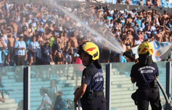 Firefighters spray water at people due to intense heat during a football game in Argentina.