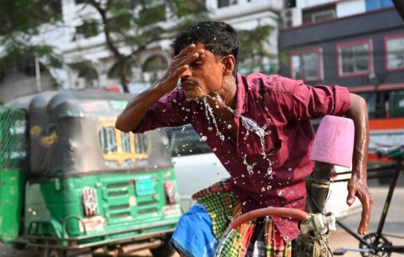 A rickshaw driver washing his face with water during a hot day in Dhaka, Bangladesh, on 15 April 2024.