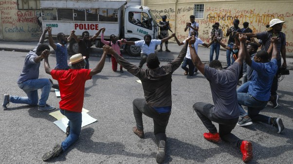 Haitians kneel outside the Justice Ministry to demand the resignation of Minister Liszt Quitel to protest kidnappings in Port-au-Prince, Haiti, on October 26, 2021.