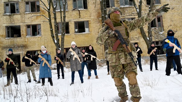 A military instructor teaches civilians holding wooden replicas of Kalashnikov rifles, during a training session in the Ukrainian capital of Kyiv on January 30, 2022.