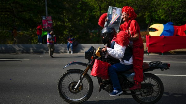 Government supporter rides on the back of a motorbike holding an image of Venezuelan President Nicolas Maduro.