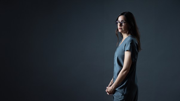 Donna Freitas standing in front of a dark background slightly in shadow