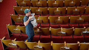 Man at a Baptist church puts hymnals in the sanctuary.