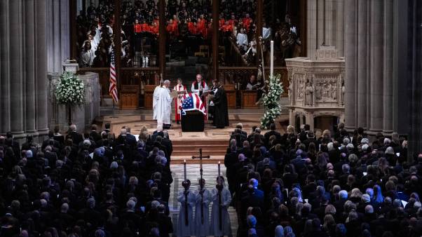 Cathedral with a flag-draped casket surrounded by clergy