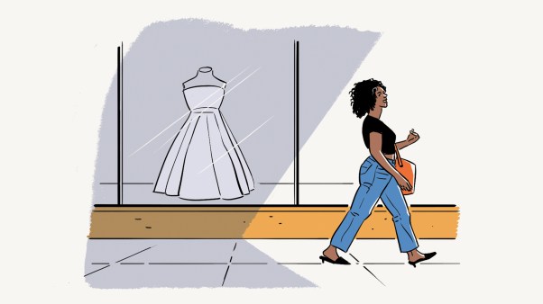 A woman walking by a store window with a wedding dress in it