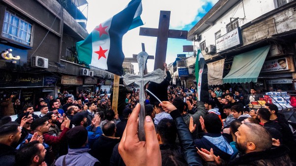 Christian Syrians lift crosses and independence-era flags as they rally in the Duweilaah area of Damascus