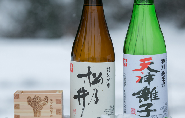 雪の上に置かれた日本酒瓶2本と升