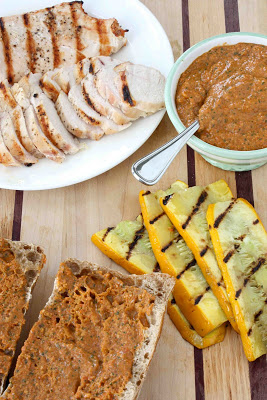 Grilled chicken and squash, pesto and ciabatta on cutting board.