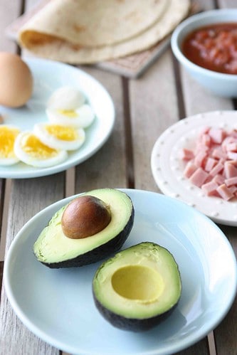 Avocado, chopped ham and hard boiled eggs on a table.