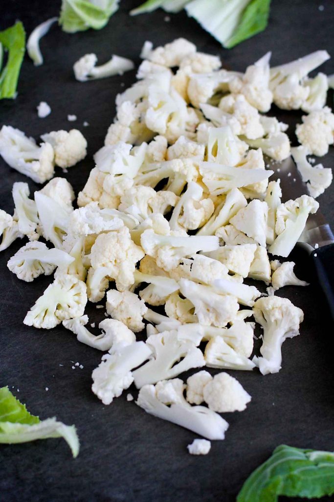 Chopped cauliflower florets on cutting board