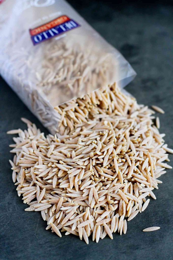 DeLallo whole wheat orzo, spilling out of bag onto cutting board.