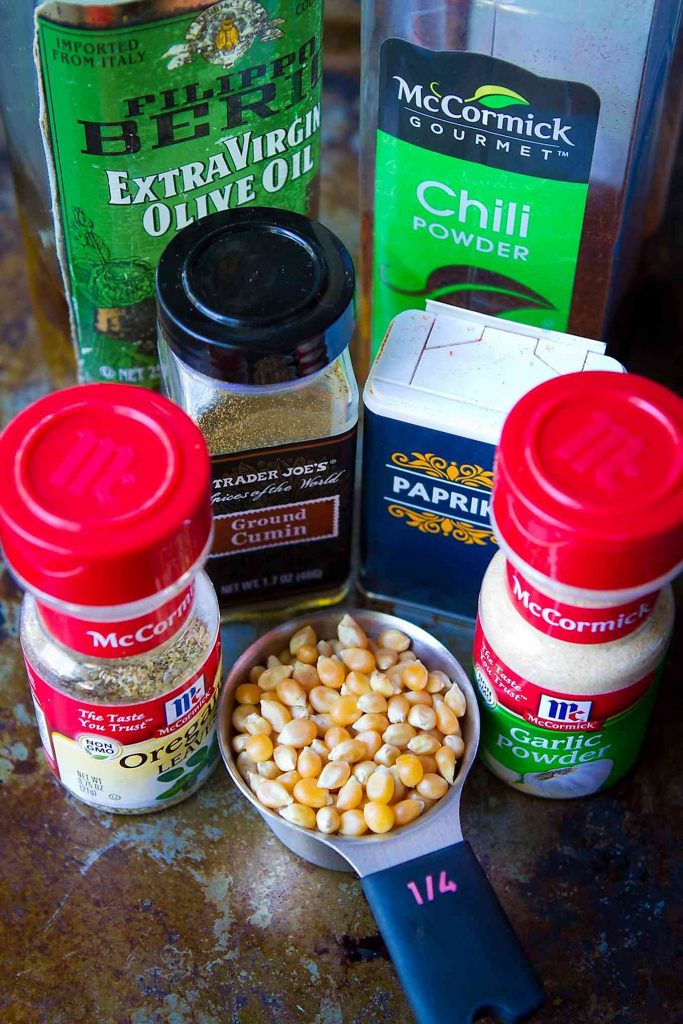 Popcorn and taco seasoning ingredients - olive oil, oregano, chili powder, cumin, paprika and garlic powder.