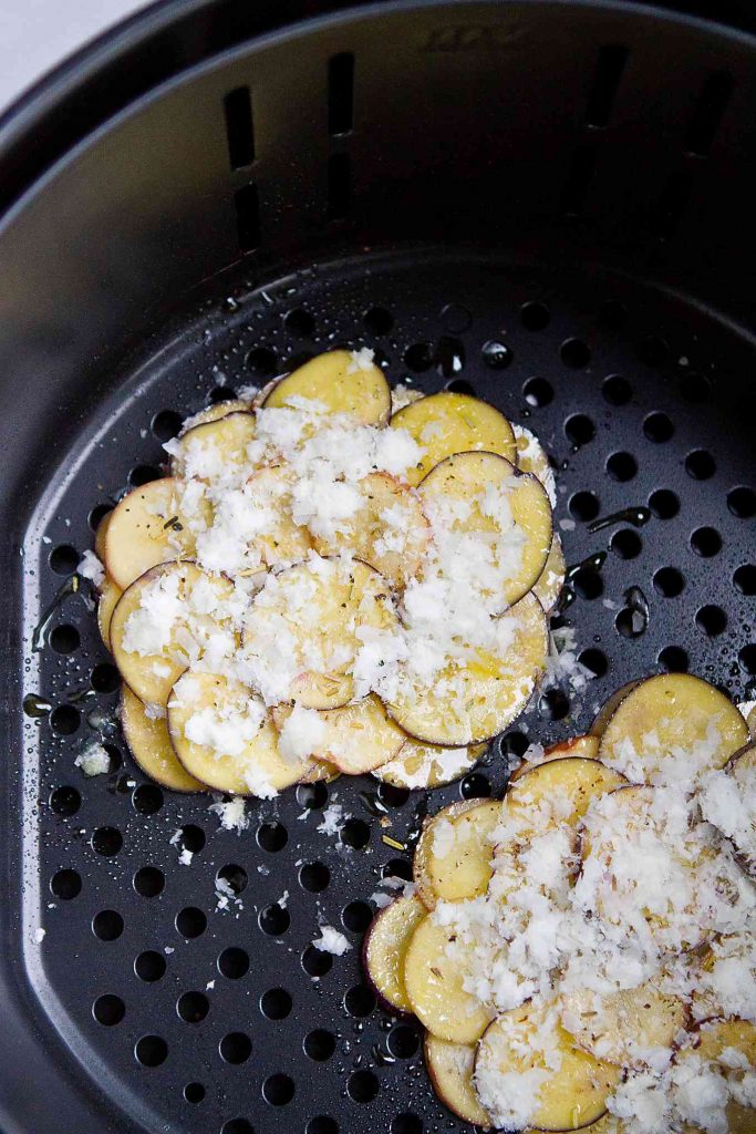 Layered potatoes with Parmesan cheese in Air Fryer basket