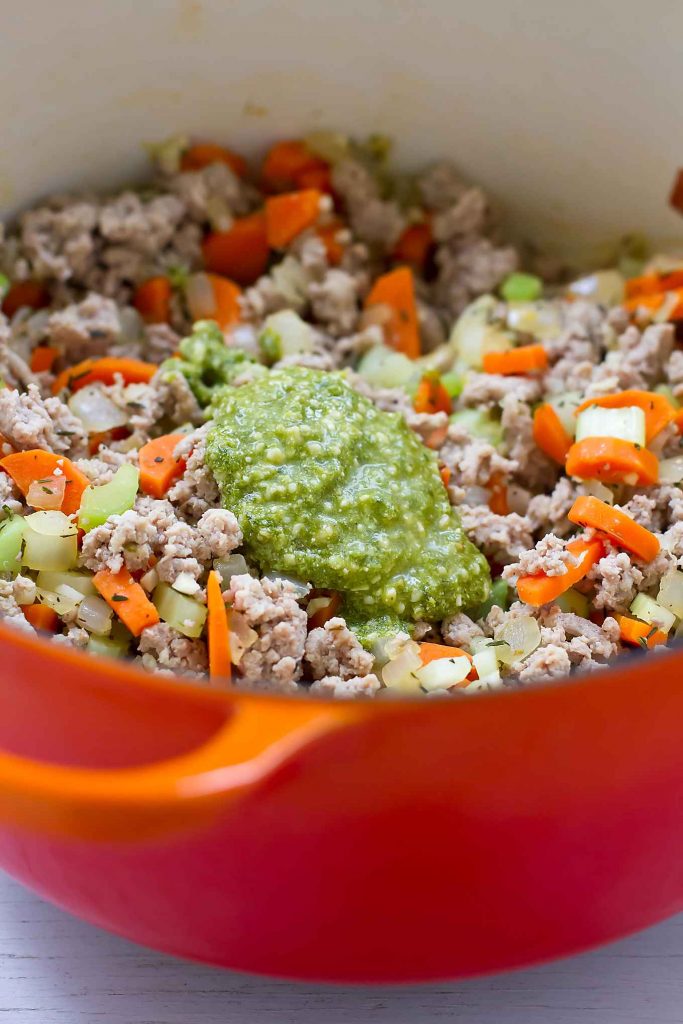 Dollop of pesto on cooked ground turkey in a large saucepan