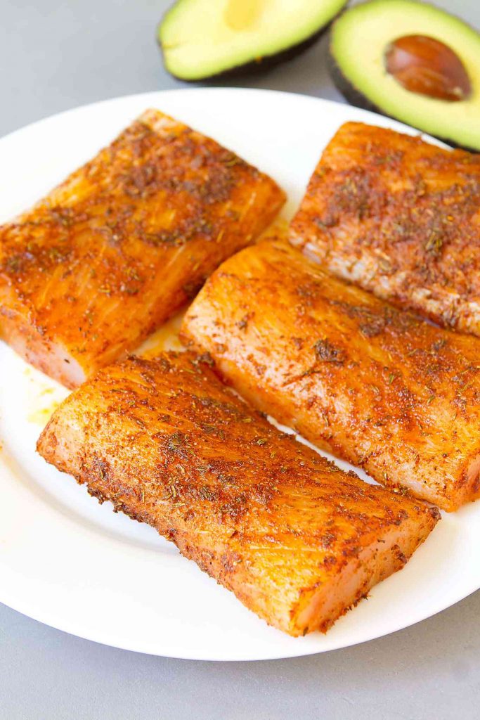 Spice rubbed, raw mahi mahi fillets on a white plate.