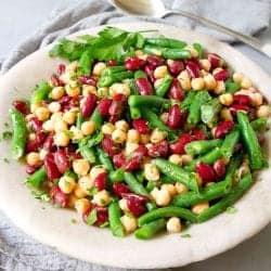 Three bean salad in a light gray stone bowl, with a gray napkin.