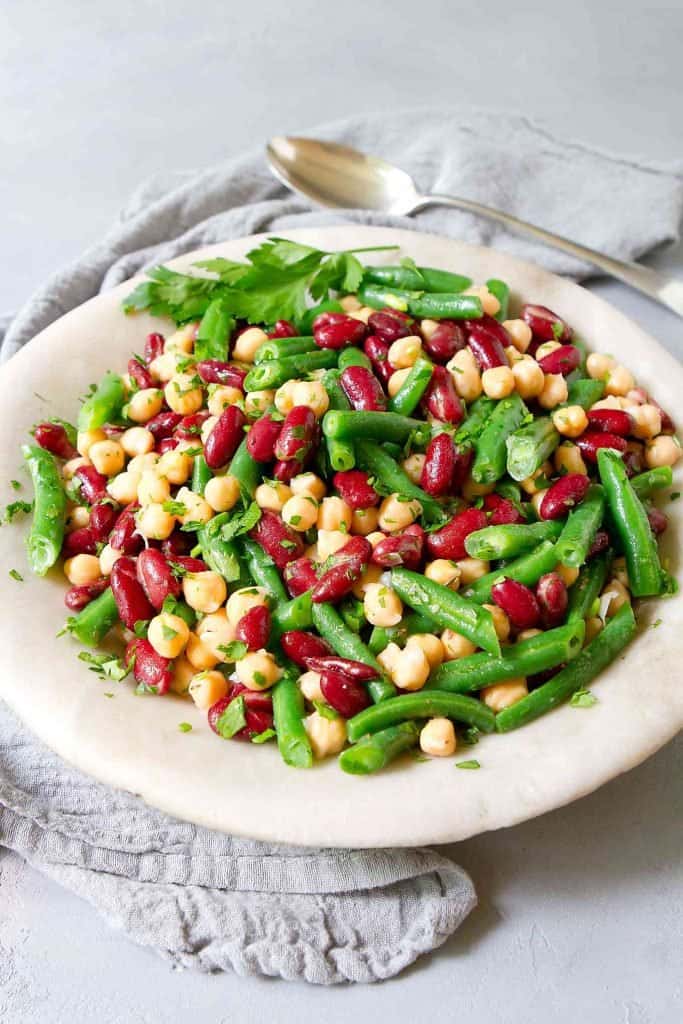 Three bean salad in a light gray stone bowl, with a gray napkin.