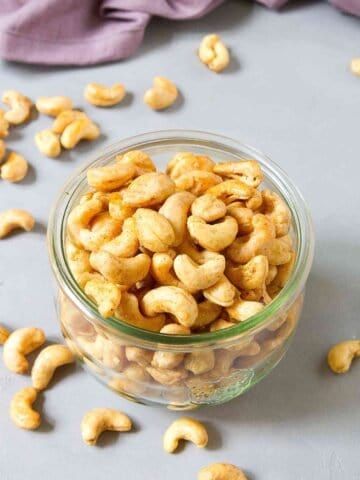 Maple roasted cashews in a glass jar. Purple napkin in background.