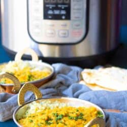 Red lentil dal in a brass bowl, with an Instant Pot in the background.