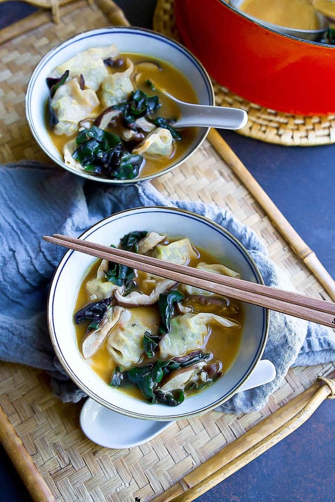 Overhead photo bowls filled with soup with wontons and vegetables.