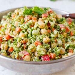 Chopped broccoli salad with chickpeas and other vegetables in a silver bowl.