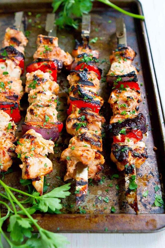 Grilled smoked paprika chicken, alternating with grilled red bell pepper and onion, on skewers.