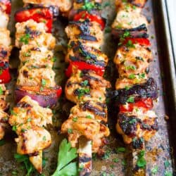 Chicken kabobs with bell peppers and onions, resting on a baking sheet.