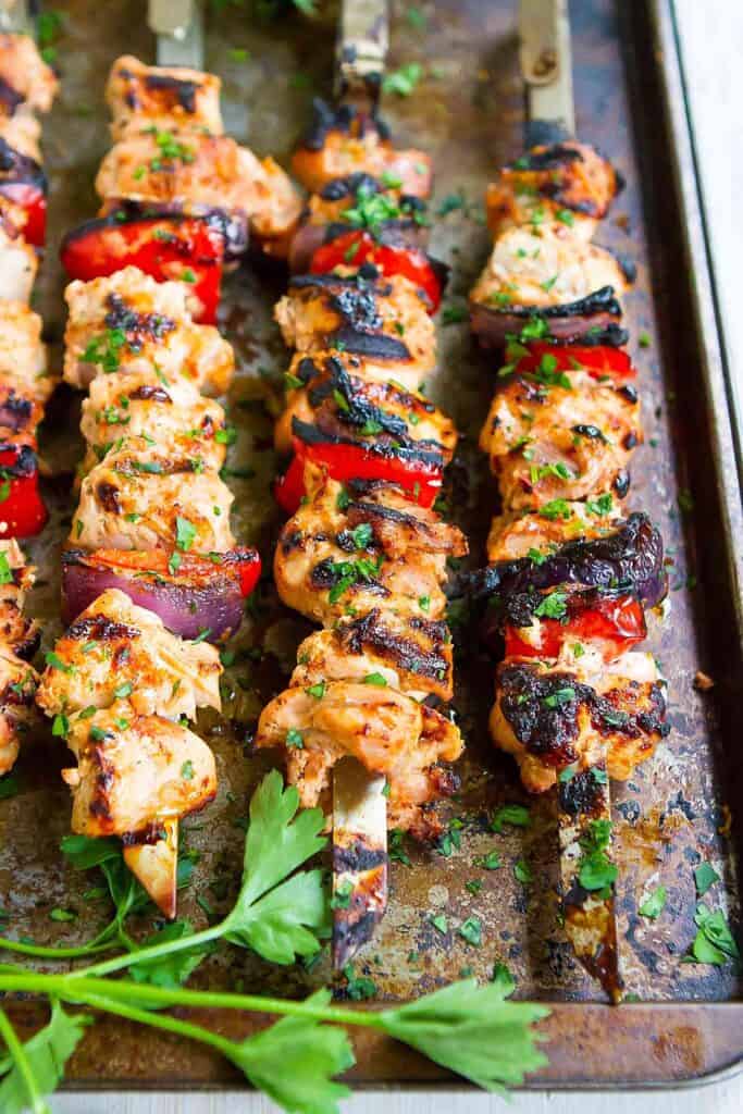 Smoked paprika chicken kabobs with bell peppers and onions, resting on a baking sheet.