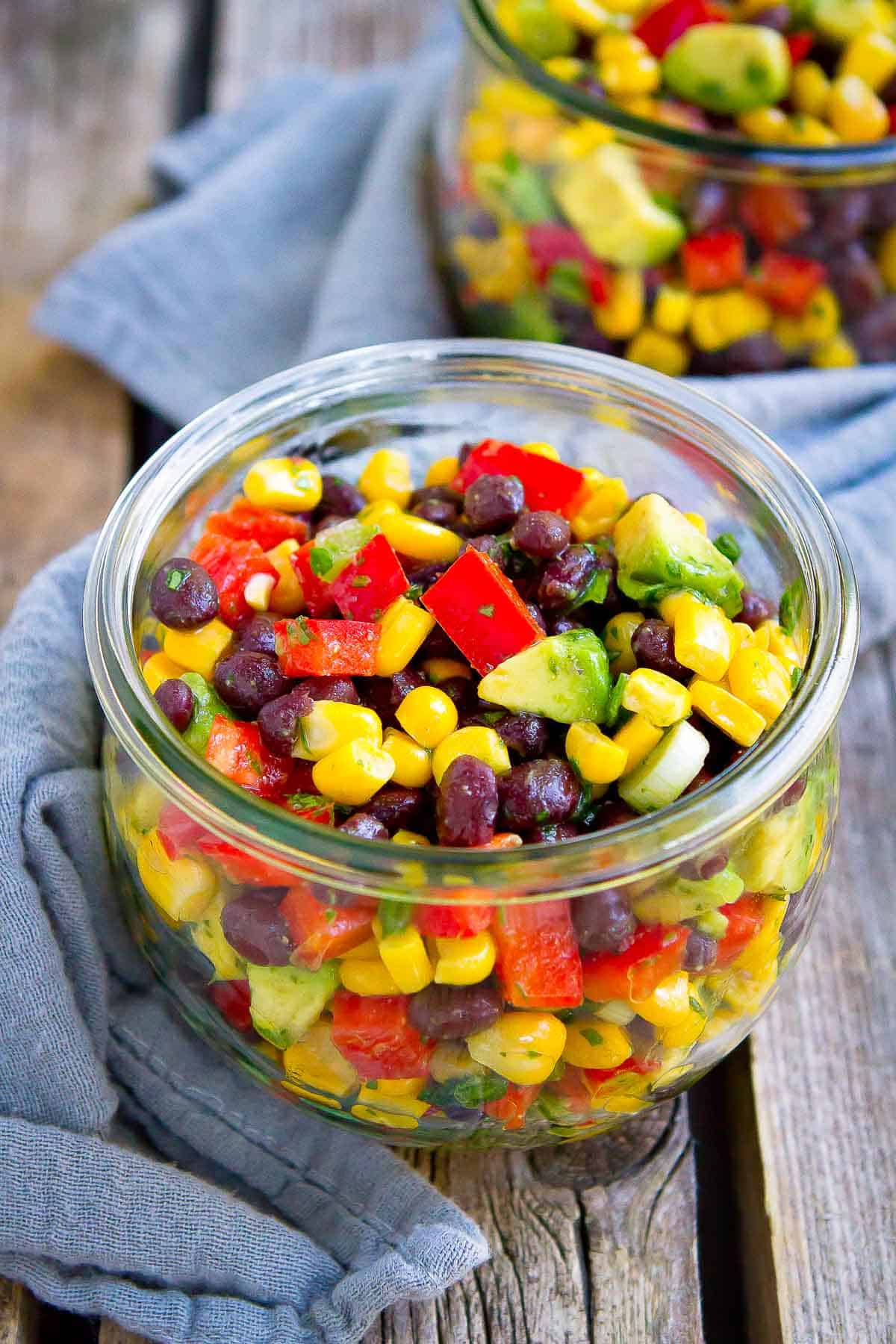 Black bean and corn salad with avocado in a glass jar.