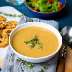 Creamy mushroom soup and thyme spring in a white bowl.