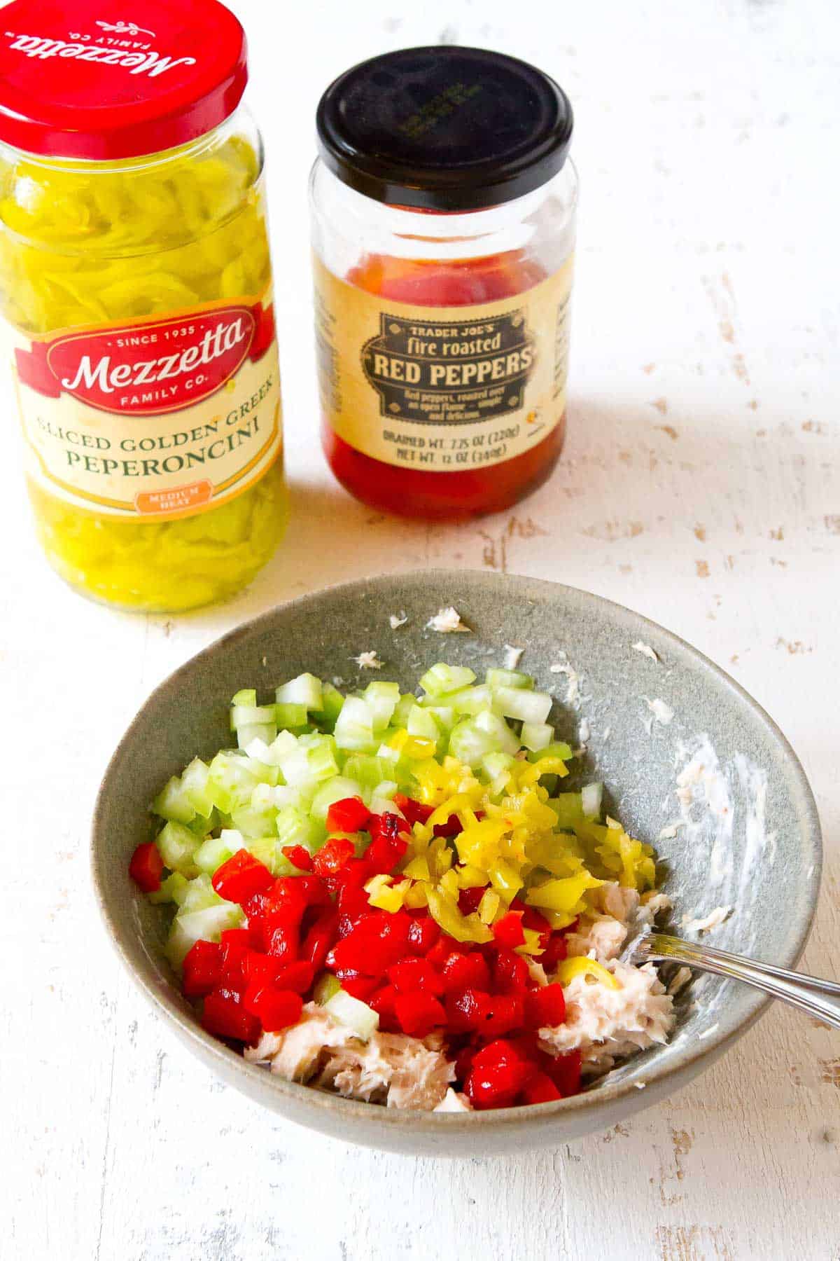 Gray bowl with tuna, mayonnaise, peppers and pepperoncini.