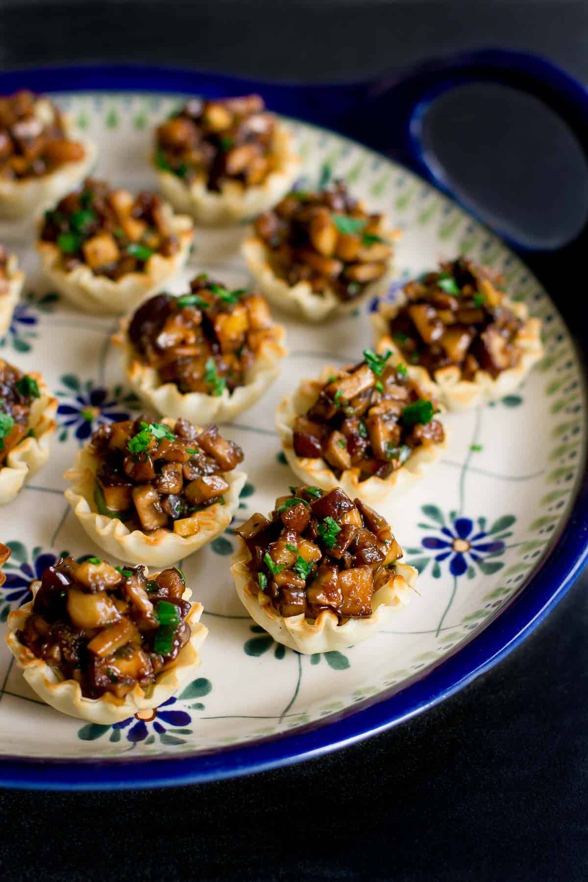 Hoisin mushroom mixture in mini phyllo cups on a blue flowered plate.