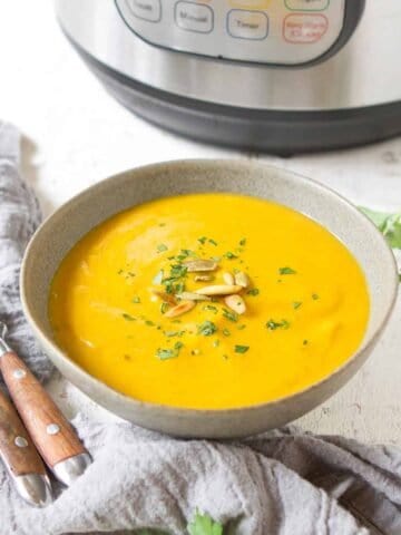 Cauliflower soup in a gray bowl, with an Instant Pot behind.