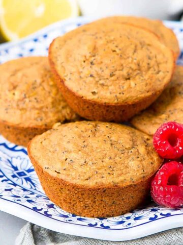 Lemon poppy seed muffins and raspberries on a blue and white plate.