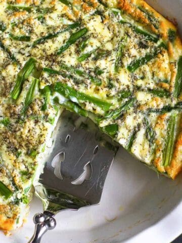 Crustless asparagus quiche and silver server in a white pie dish.