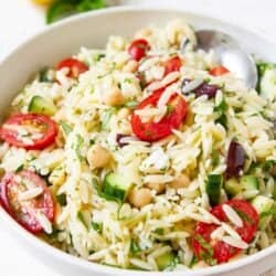 Orzo pasta salad with vegetables in a white bowl.