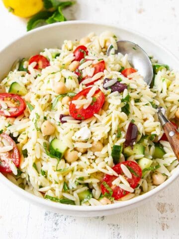 Orzo pasta salad with vegetables in a white bowl.