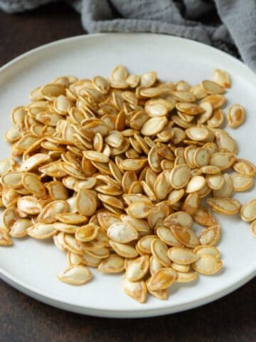 Air fryer pumpkin seeds on a white plate.