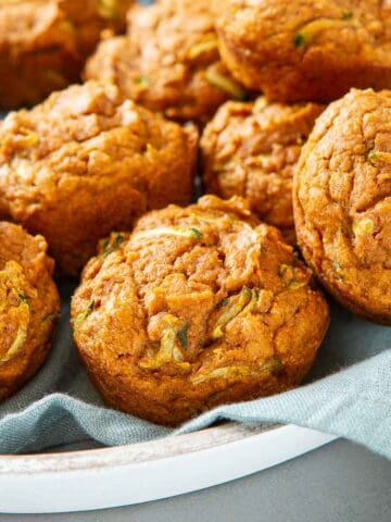 Pumpkin zucchini muffins on a blue napkin and white tray.