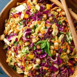 Slaw with chickpeas and peanut dressing in a large wooden salad bowl.